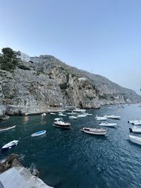 Sailboats moored on sea against clear blue sky