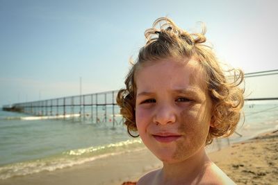 Portrait of girl with messy face at beach against sky