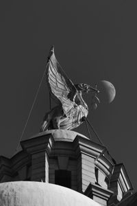 Low angle view of statue against building against clear sky