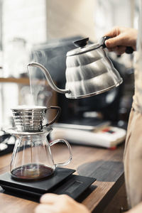 Cropped image of barista pouring boiling water in coffee filter