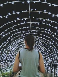 Rear view of woman walking in illuminated archway at night