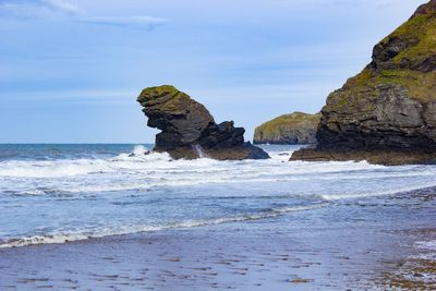 Rock formation on beach against sky