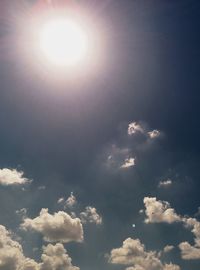 Low angle view of sun shining through clouds