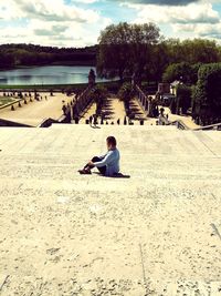Full length of woman sitting on shore against sky