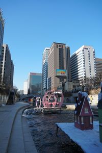 Vehicles on road by buildings against clear sky