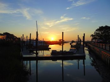 Sailboats moored at harbor against sky during sunset