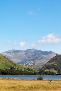 Scenic view of lake and mountains against blue sky