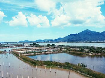 High angle view of canal by city against cloudy sky