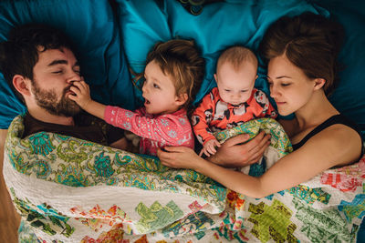 Family of four crowded in bed needing personal space and pushing away