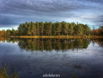 Scenic view of lake by trees against sky