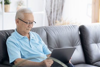 Midsection of man using mobile phone while sitting on sofa at home