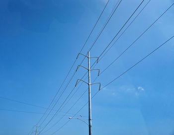 Low angle view of electricity pylon against blue sky