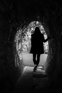 Rear view of woman walking in tunnel