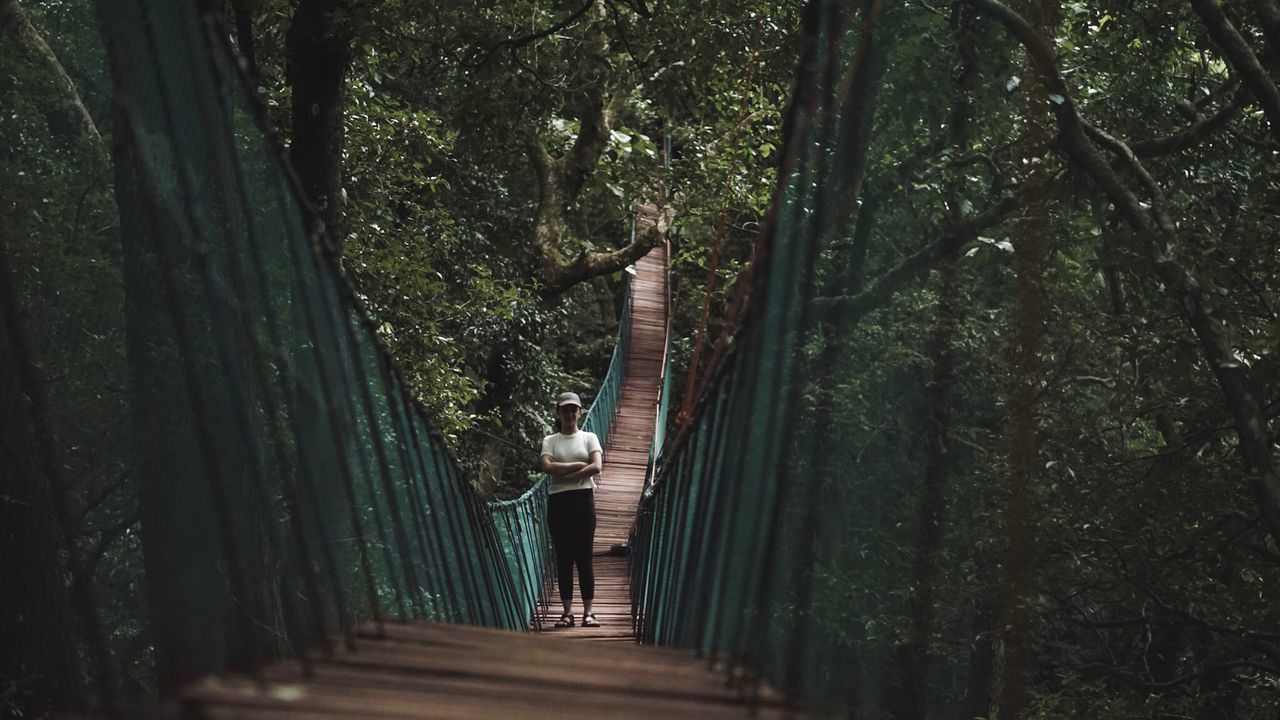 WOMAN STANDING BY TREE IN FOREST