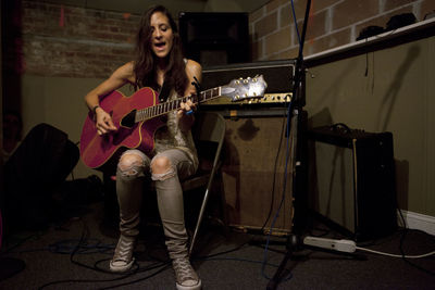 Young woman playing an acoustic guitar at band practice