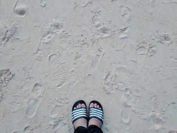 Low section of person standing on sand