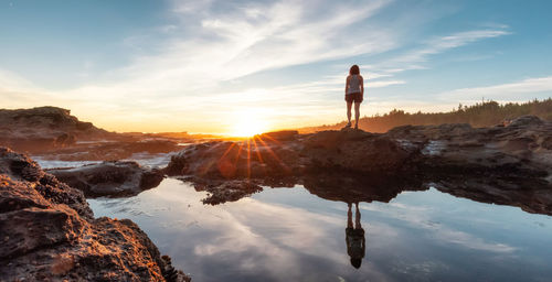 Man standing on rock against sky during sunset