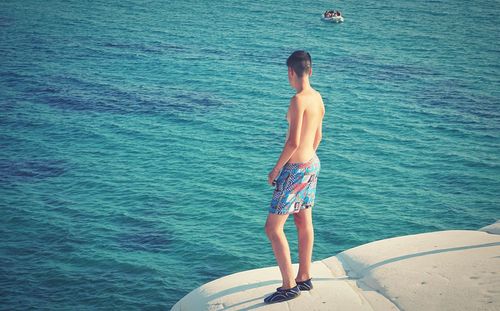 Rear view of shirtless man standing in sea