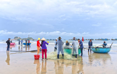 People at beach against sky