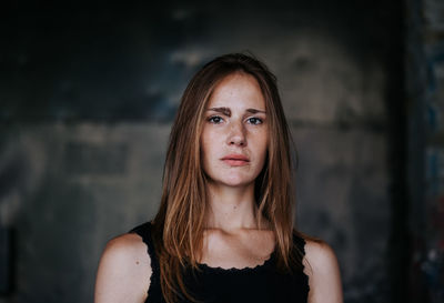 Portrait of young woman standing against wall