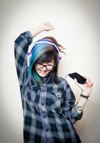 Young woman using phone while standing against white background