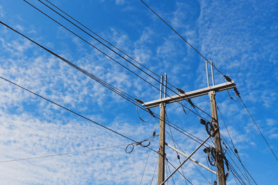 Low angle view of electricity pylon against blue sky