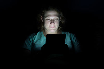 Woman using digital tablet against black background