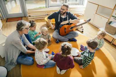 Children and teachers singing and making music in kindergarten