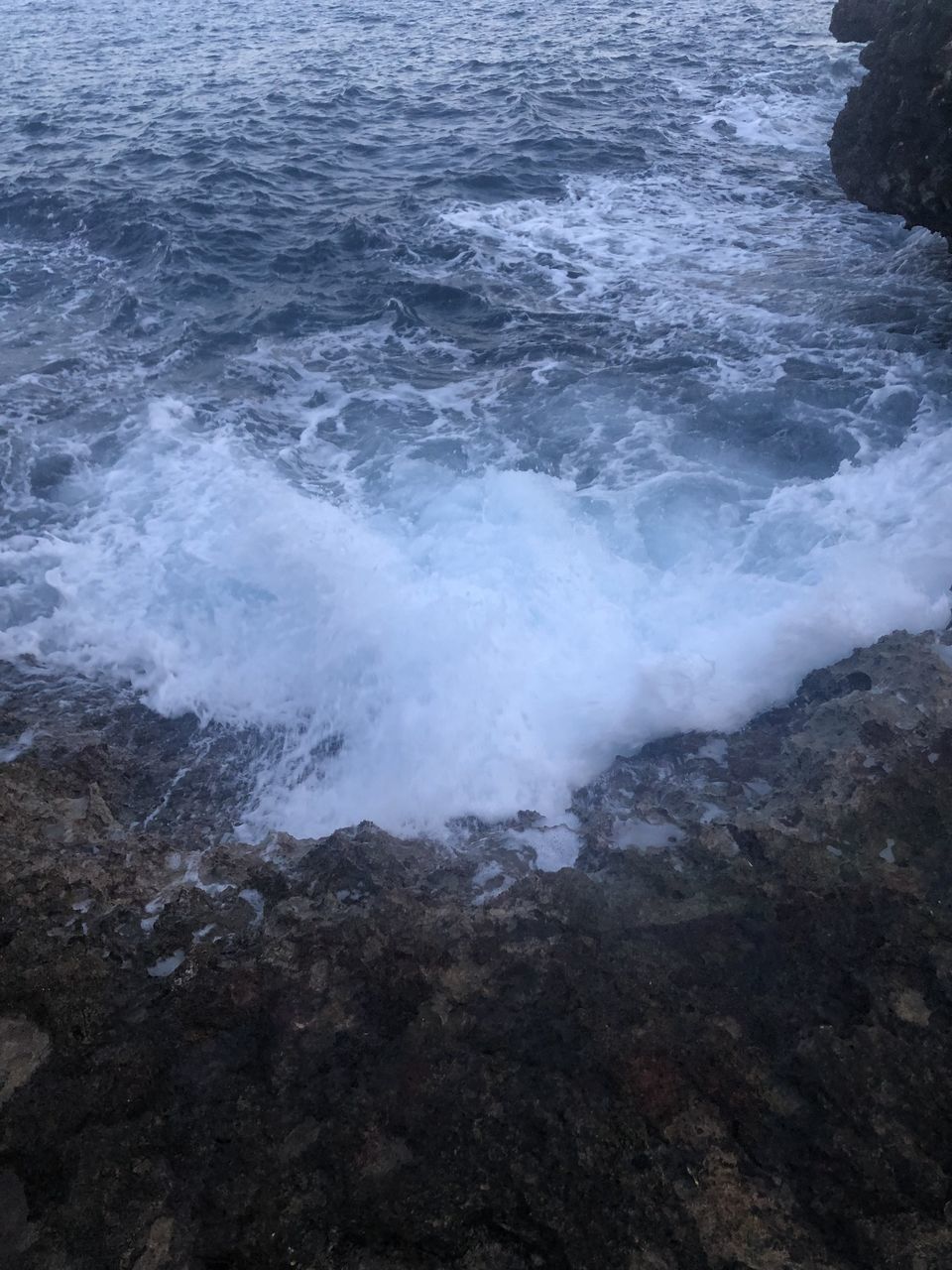 HIGH ANGLE VIEW OF WAVES BREAKING ON ROCK