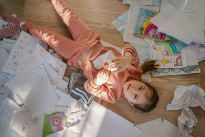 A girl among the mess and scattered sheets in the room.