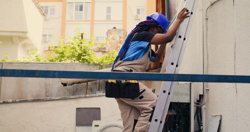 Side view of young woman standing against built structures