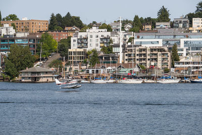 Sailboats in sea by townscape against sky