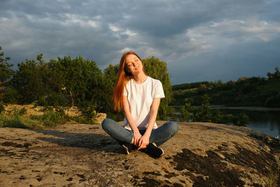 Portrait of smiling woman sitting against sky