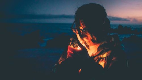 Close-up of woman igniting cigarette at beach during sunset