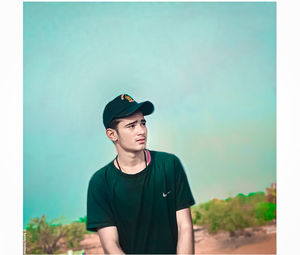 Portrait of young man looking away against blue sky