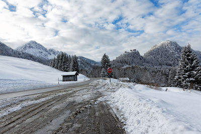 Snow covered road by mountain against sky