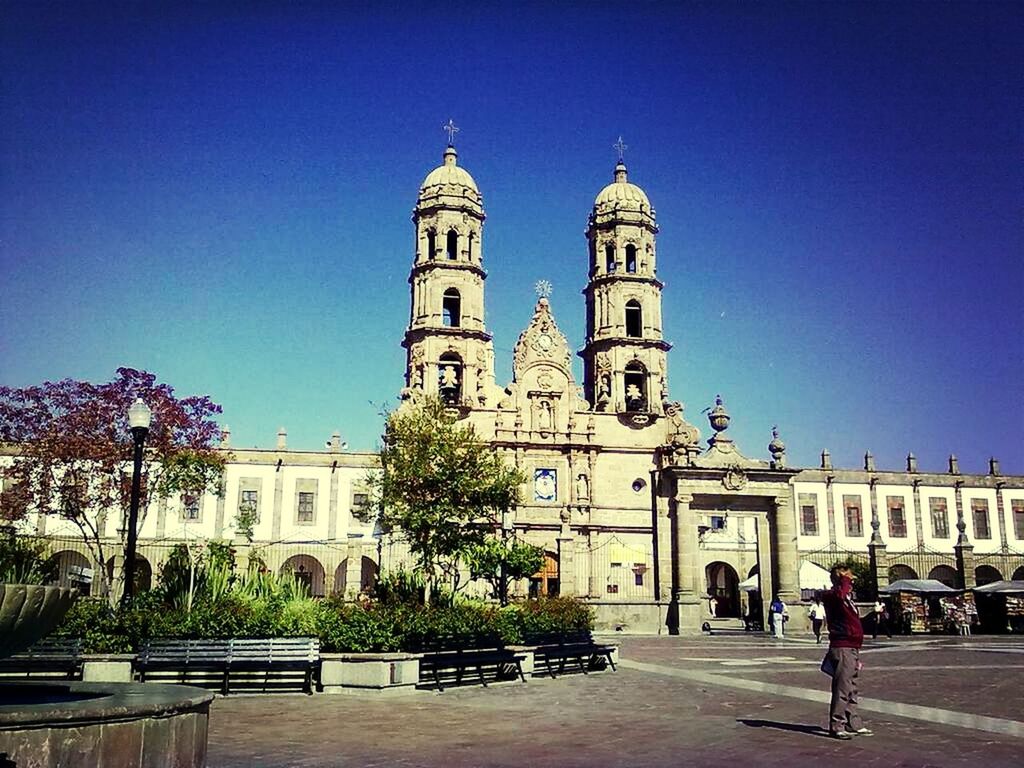 building exterior, architecture, built structure, place of worship, church, religion, blue, clear sky, spirituality, facade, tree, cathedral, low angle view, incidental people, sky, cross, sunlight