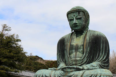 Statue of buddha against cloudy sky