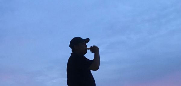 Side view of silhouette man photographing against sky