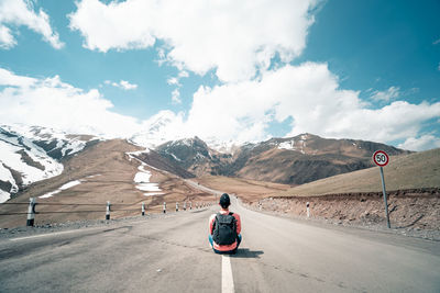 Rear view of man standing on road against mountain range