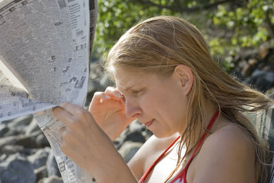 Side view of woman reading newspaper outdoors