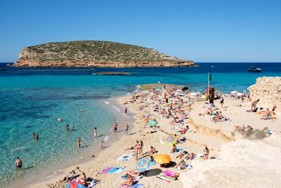 People on beach against clear blue sky