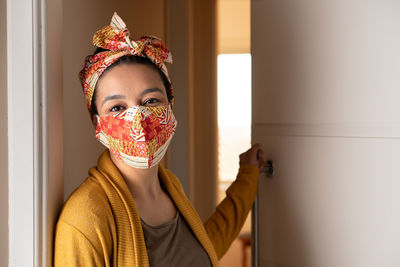 Portrait of smiling woman wearing mask standing against wall