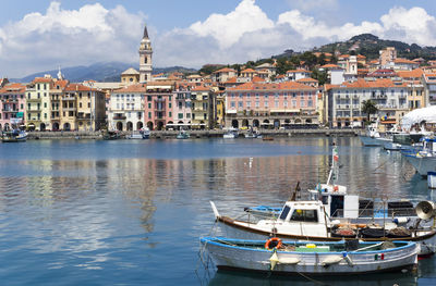 Sailboats moored in sea against buildings in city