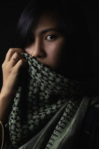 Portrait of young woman against black background