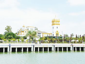 View of buildings by river against sky