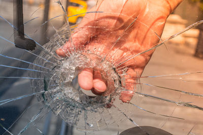 Close-up of hand touching broken glass