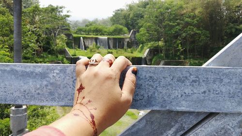 Close-up of woman with henna tattoo on hand touching fence