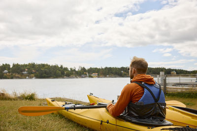 Rear view of man sitting in kayak and looking at sea