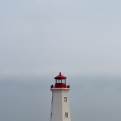 Lighthouse by sea against sky